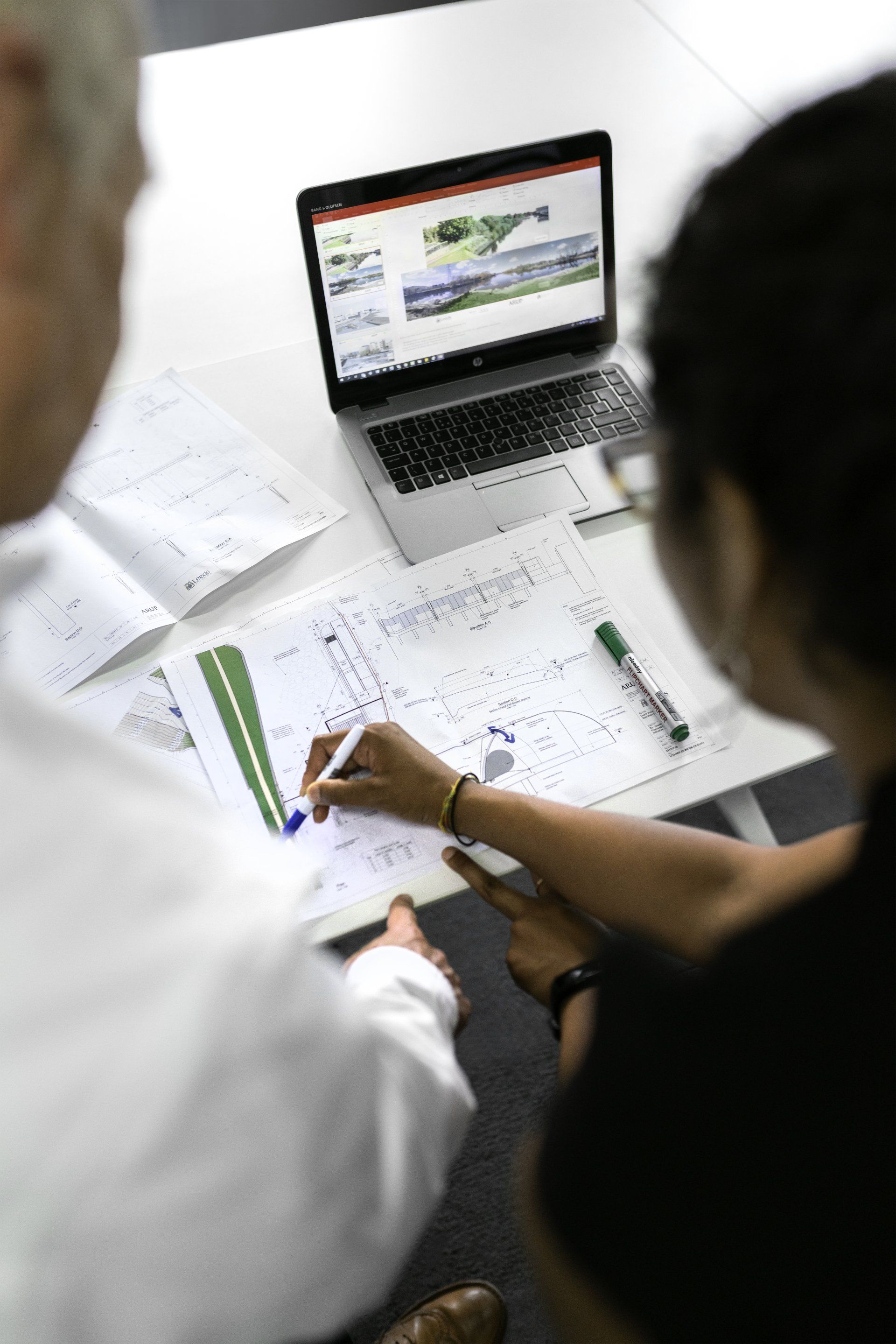 A man and a woman are sitting at a table looking at a laptop.